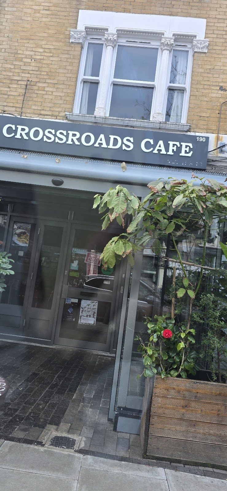 The Crossroads Cafe shopfront on Bellenden Road, seen from across the street with its windows and planters